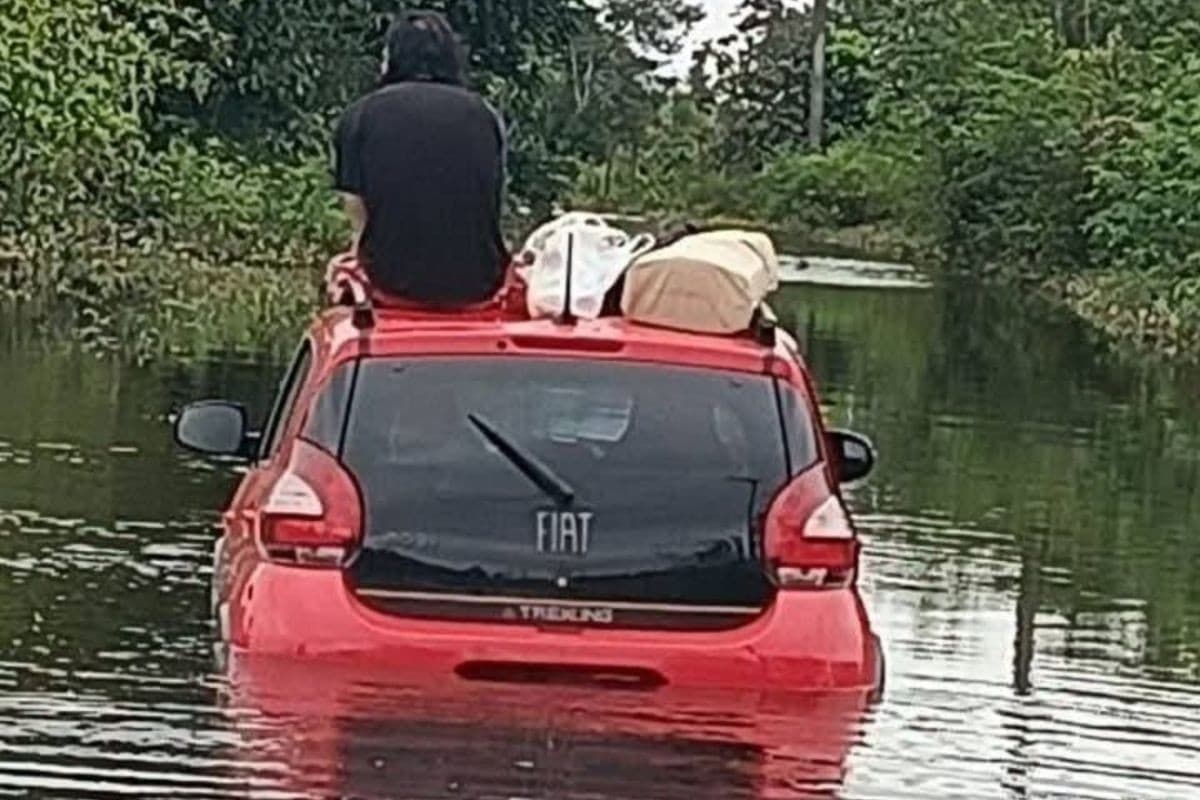 Motorista sobe em teto de carro após ficar ilhado durante enchente no litoral de SP